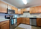 Thumbnail 10 of 45 - an empty kitchen with wooden cabinets and stainless steel appliances. Fargo, ND Urban Plains Apartments
