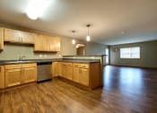 Thumbnail 22 of 45 - an empty kitchen and living room with wood floors and wood cabinets. Fargo, ND Urban Plains Apartments