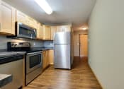Thumbnail 34 of 45 - an empty kitchen with stainless steel appliances and wooden cabinets. Fargo, ND Urban Plains Apartments