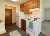 Thumbnail 8 of 34 - a kitchen with white appliances and wooden cabinets and a white refrigerator. Fargo, ND Islander Apartments