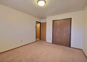 Thumbnail 11 of 26 - a spacious living room with carpet and a door to a bedroom. Fargo, ND Village West Apartments