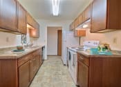 Thumbnail 12 of 26 - a kitchen with white appliances and wooden cabinets. Fargo, ND Village West Apartments