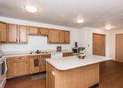 Thumbnail 5 of 10 - Grand Forks, ND Vista Apartments. a kitchen with wooden cabinets and a white counter top