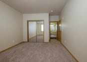 Thumbnail 21 of 61 - A bedroom with carpet and a mirror on the closet door. West Fargo, ND West Lake Apartments.