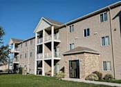 Thumbnail 28 of 28 - A large apartment building with a grassy area in front of it. Fargo, ND Eagle Run Apartments.