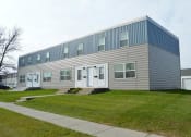Thumbnail 28 of 28 - West Fargo, ND Sheyenne Terrace. A gray building with white doors and a green lawn