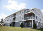 Thumbnail 60 of 61 - An exterior view of a gray apartment building with balconies. West Fargo, ND West Lake Apartments.