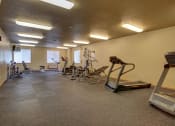 Thumbnail 58 of 61 - A gym with cardio equipment and weights on the floor. West Fargo, ND West Lake Apartments.