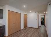 Thumbnail 36 of 49 - a long hallway with white walls and wooden floors and wooden doors. Fargo, ND Lake Crest Apartments