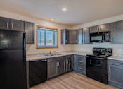 Thumbnail 35 of 49 - a kitchen with black appliances and wood flooring. Fargo, ND Lake Crest Apartments