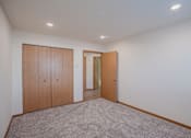 Thumbnail 40 of 49 - a living room with carpet and a door to a hallway. Fargo, ND Lake Crest Apartments
