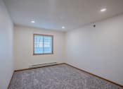 Thumbnail 39 of 49 - an empty living room with carpet and a window. Fargo, ND Lake Crest Apartments