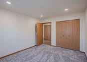 Thumbnail 38 of 49 - a living room with a carpeted floor and a door to a hallway. Fargo, ND Lake Crest Apartments