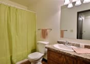 Thumbnail 10 of 11 - a bathroom with a green shower and a sink and a toilet. Fargo, ND Westcourt Apartments