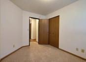 Thumbnail 8 of 11 - a bedroom with a closet and a door to a hallway. Fargo, ND Westcourt Apartments