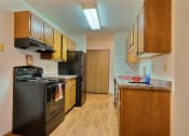 Thumbnail 4 of 11 - a kitchen with black appliances and wooden cabinets. Fargo, ND Westcourt Apartments