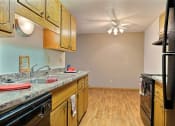 Thumbnail 5 of 11 - a kitchen with wooden cabinets and a sink and a refrigerator. Fargo, ND Westcourt Apartments
