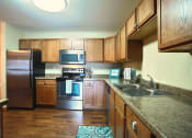 Thumbnail 7 of 21 - a kitchen with stainless steel appliances and wooden cabinets. Fargo, ND Wolf Creek Apartments