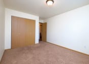Thumbnail 10 of 11 - a bedroom with a closet and a door to a hallway. Moorhead, MN Woodstone Apartments