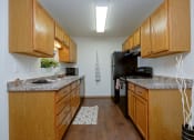Thumbnail 4 of 11 - a kitchen with wood cabinets and black appliances and a counter top. Moorhead, MN Woodstone Apartments