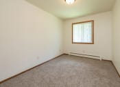 Thumbnail 11 of 34 - a bedroom with carpet and a window. Fargo, ND Islander Apartments