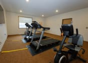 Thumbnail 21 of 23 - a fitness room with two treadmills and a tv. Fargo, ND North Sky Apartments