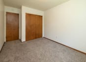 Thumbnail 12 of 34 - a bedroom with a closet and a door to a hallway. Fargo, ND Islander Apartments