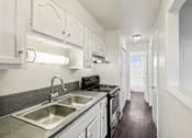 Thumbnail 7 of 23 - A kitchen with white cabinets and a stainless steel sink.