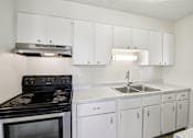 Thumbnail 5 of 23 - A kitchen with white cabinets and a black stove top oven.