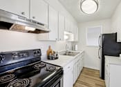 Thumbnail 4 of 23 - A kitchen with a black stove top oven and white cabinets.