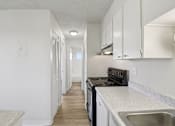 Thumbnail 6 of 23 - A kitchen with white cabinets and a black stove top oven.