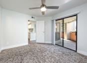 Thumbnail 9 of 36 - an empty living room with a ceiling fan and sliding glass doors to a patio