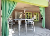 Thumbnail 15 of 25 - a patio with a table and chairs and a green curtain