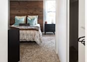 Thumbnail 11 of 23 - a bedroom with a bed and a wooden accent wall