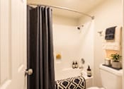 Thumbnail 17 of 34 - A bathroom with a white tub and a black and white patterned towel.