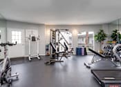 Thumbnail 24 of 34 - A spacious gym with a variety of equipment including treadmills, stationary bikes, and weight machines.
