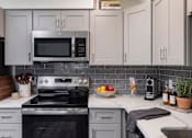 Thumbnail 3 of 34 - A modern kitchen with a stove, microwave, and oven.
