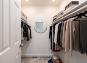 Thumbnail 16 of 34 - A hallway with a mirror and clothes hanging on the wall.