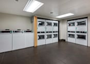 Thumbnail 26 of 35 - a laundry room with several washes and dryers in it