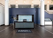 Thumbnail 19 of 35 - a reception desk in a lobby with a blue wall and white pillars