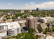Thumbnail 16 of 18 - A cityscape with buildings and trees under a blue sky.