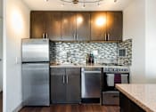 Thumbnail 4 of 18 - A modern kitchen with dark wood cabinets and stainless steel appliances.