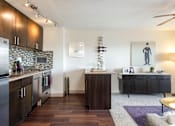 Thumbnail 1 of 18 - A modern kitchen with dark wood floors and a marble backsplash.