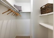 Thumbnail 23 of 33 - a walk in closet with white walls and shelves and wooden hangers
