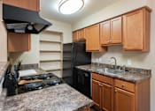 Thumbnail 4 of 16 - a kitchen with black appliances and granite counter tops and wooden cabinets