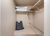 Thumbnail 8 of 16 - a walk in closet with pillows and a bag on a shelf in a closet
