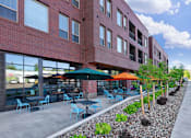 Thumbnail 18 of 29 - A red brick building with tables and chairs outside.