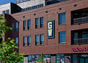 Thumbnail 25 of 29 - A red brick building with a green sign that says GW on it.