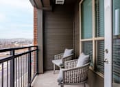 Thumbnail 9 of 29 - Two chairs are on a balcony with a view of the city.