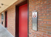 Thumbnail 14 of 31 - a red door with a sign on the side of a brick building